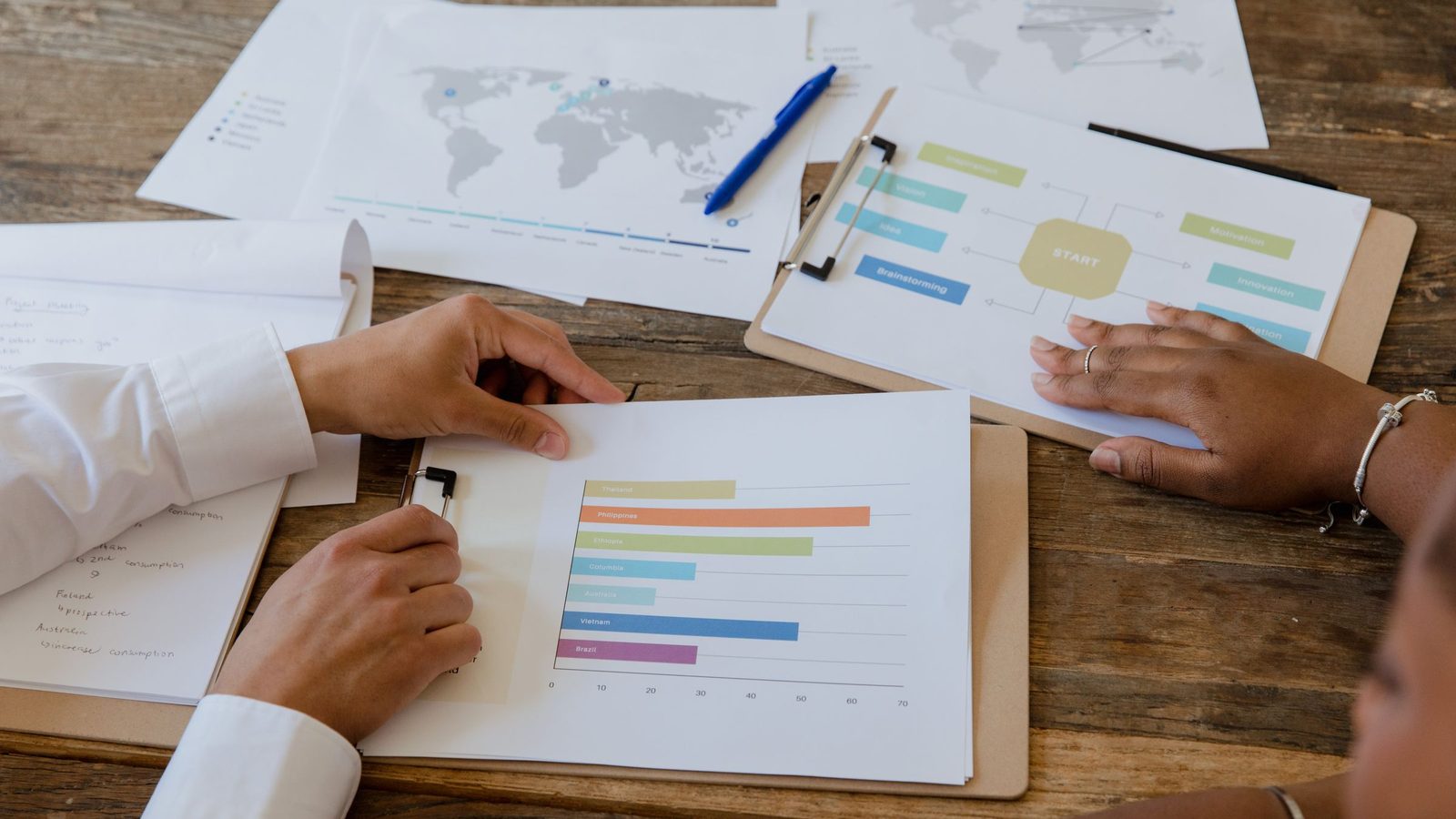 Top view of colleagues discussing charts and graphs on a wooden table during a business meeting